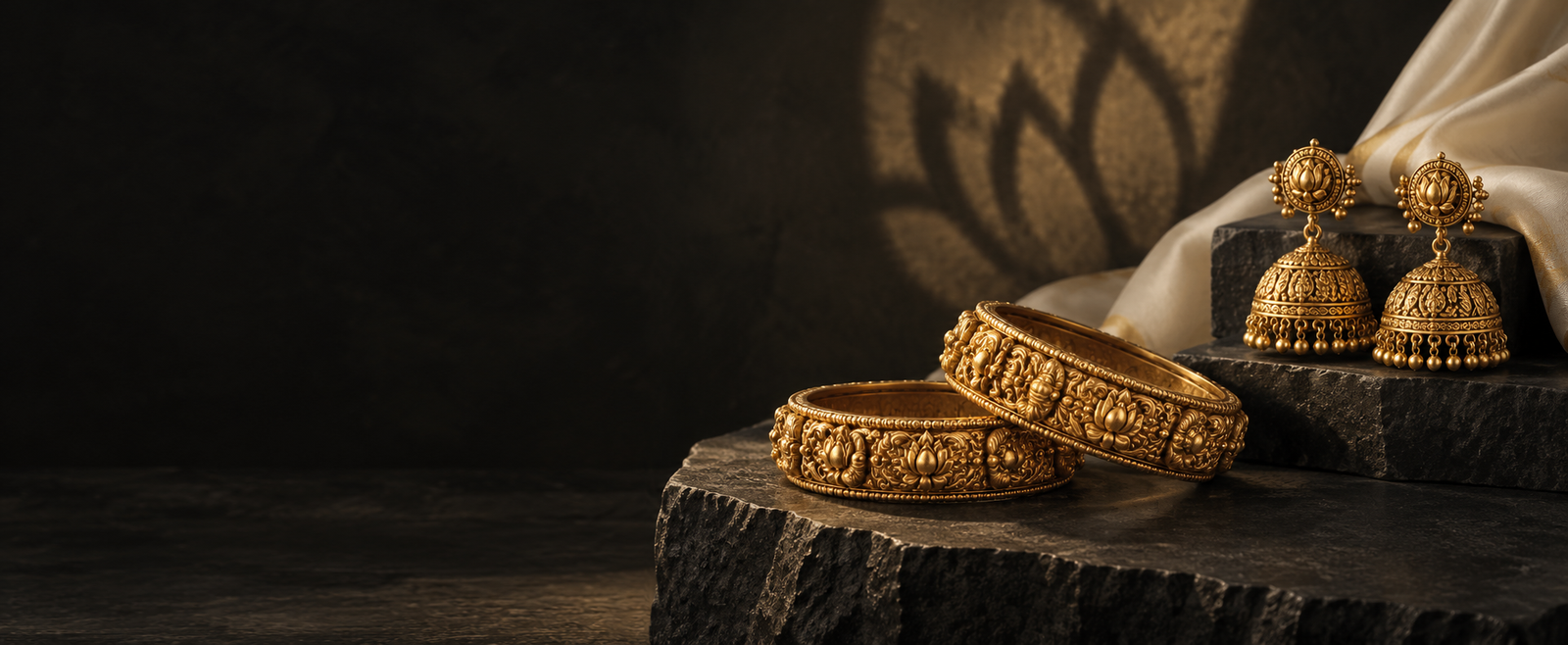 Ornate gold bangles and jhumka earrings on a charcoal display